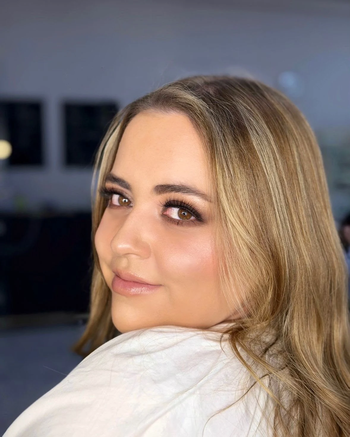 Clienta que voltea por encima del hombro con ahumado suave y labios nude.