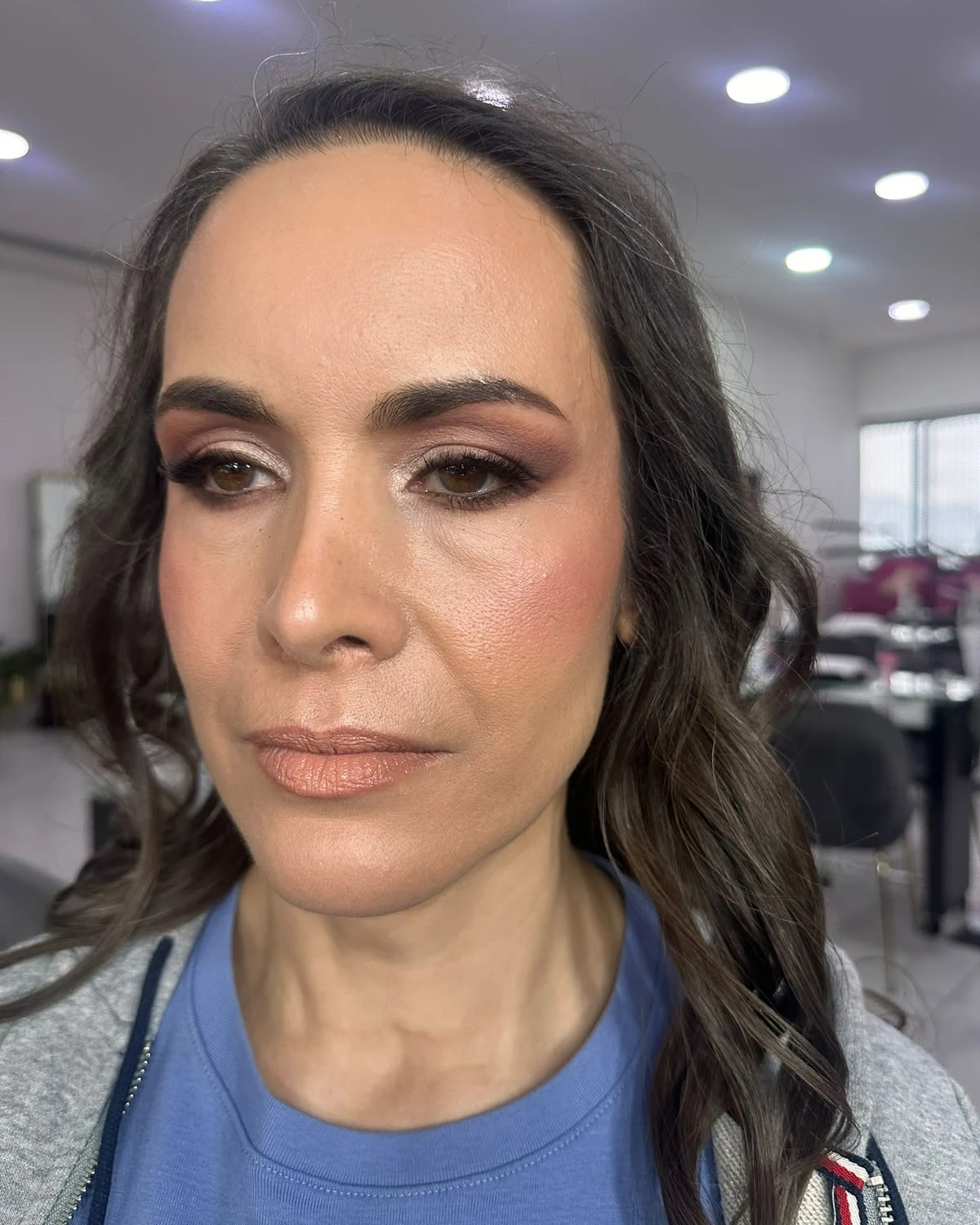 Clienta con ahumado ciruela difuminado y labios nude; mira de frente, seria.